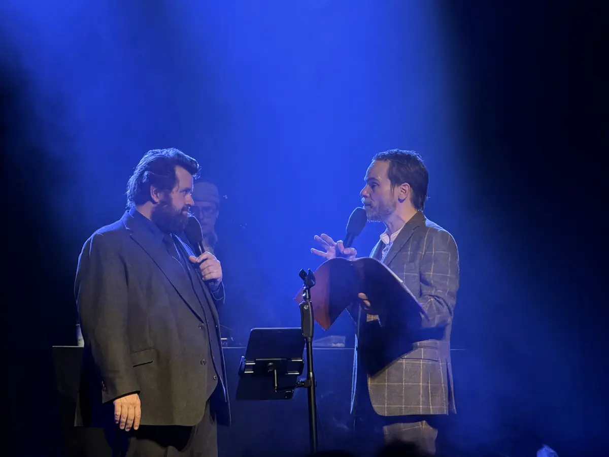 Antoine Monot und Wanja Mues im Dialog auf der Bühne, beide mit Mikrofon